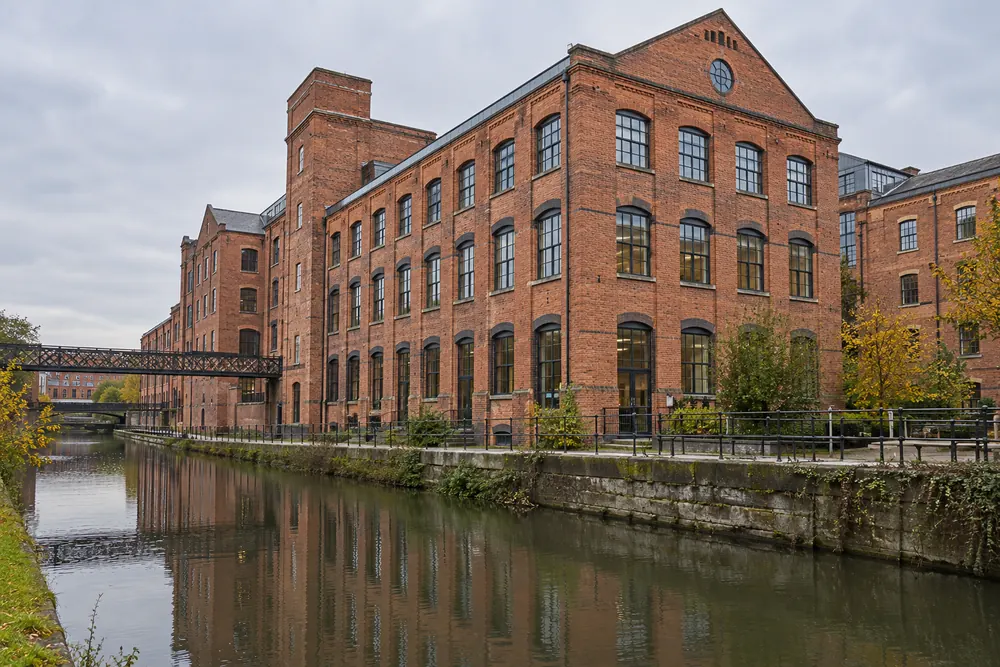 Brick commercial buildings beside Nottingham’s canal, reflected in the water
